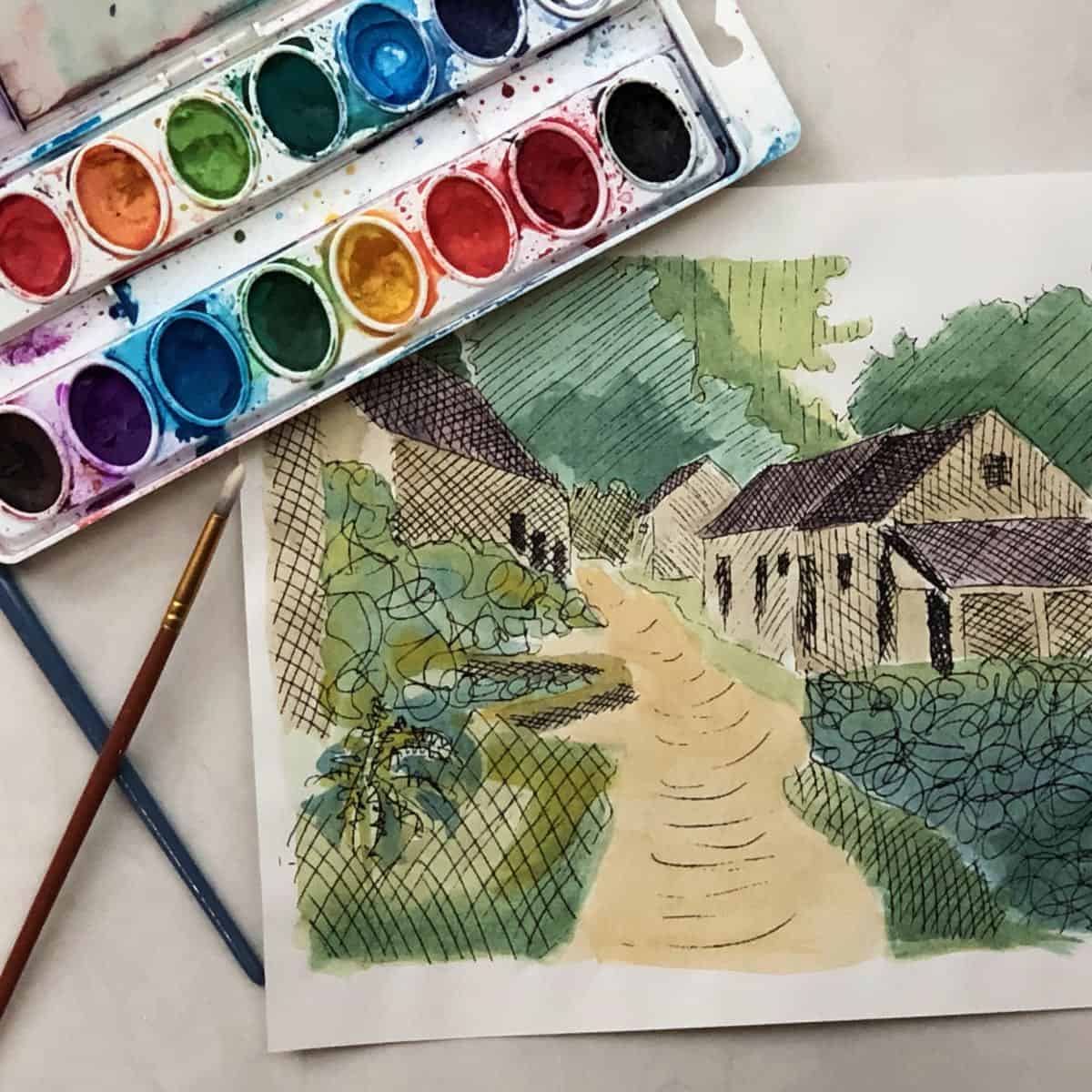 Cross hatched drawing of some French countryside houses on a dirt road with some greenery and trees in the background next to a watercolor painting set and some paintbrushes.
