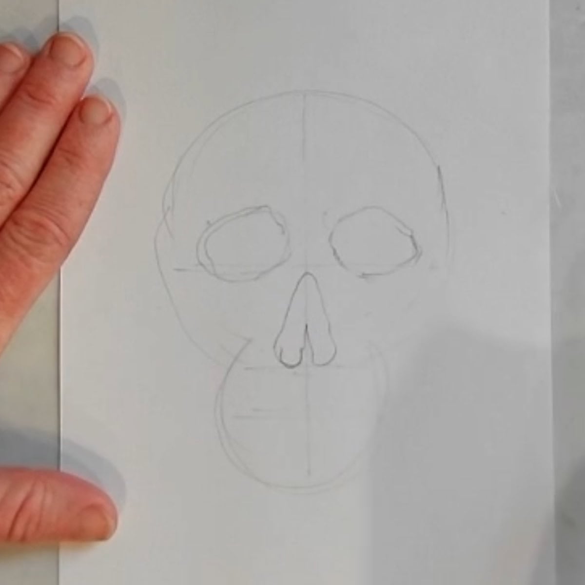 Beginning drawing of a skull with eyes and nose sketched in. 