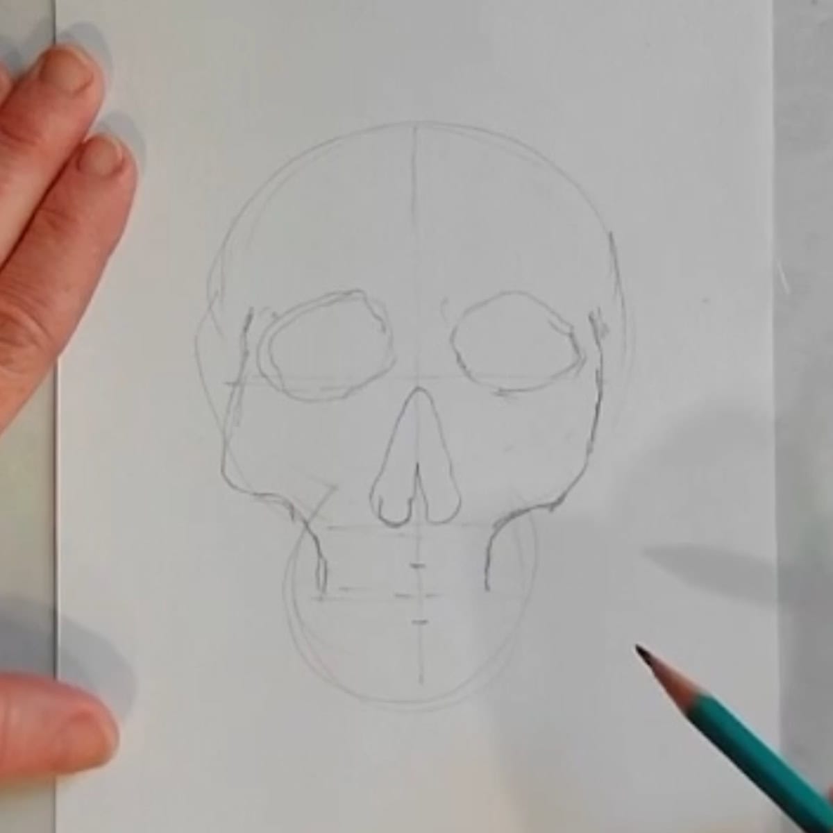 Beginning sketch of a skull with artist drawing in cheekbones with a pencil. 