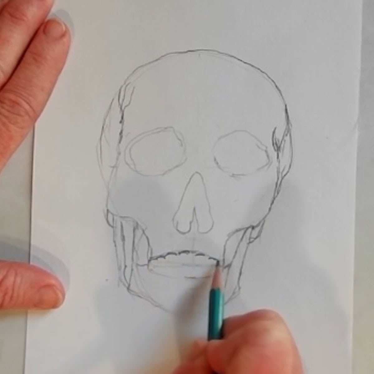 Beginning drawing of a skull with artist drawing in the mouth with a pencil. 