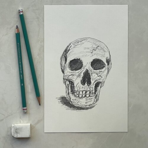 Drawing of a skull in pencil next to drawing pencils and an eraser.