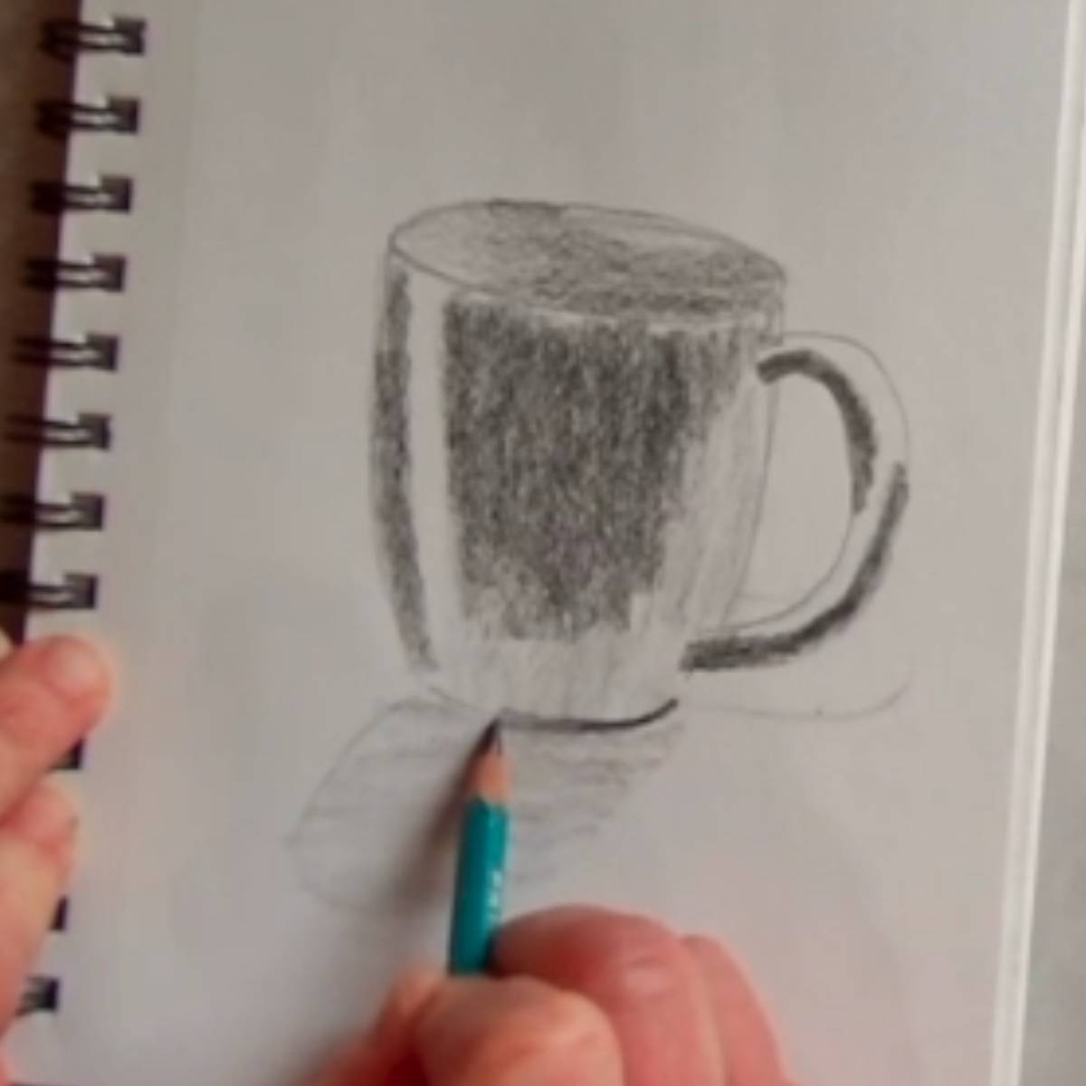 Adding in the shadows and shading to a drawing of a coffee mug in pencil.