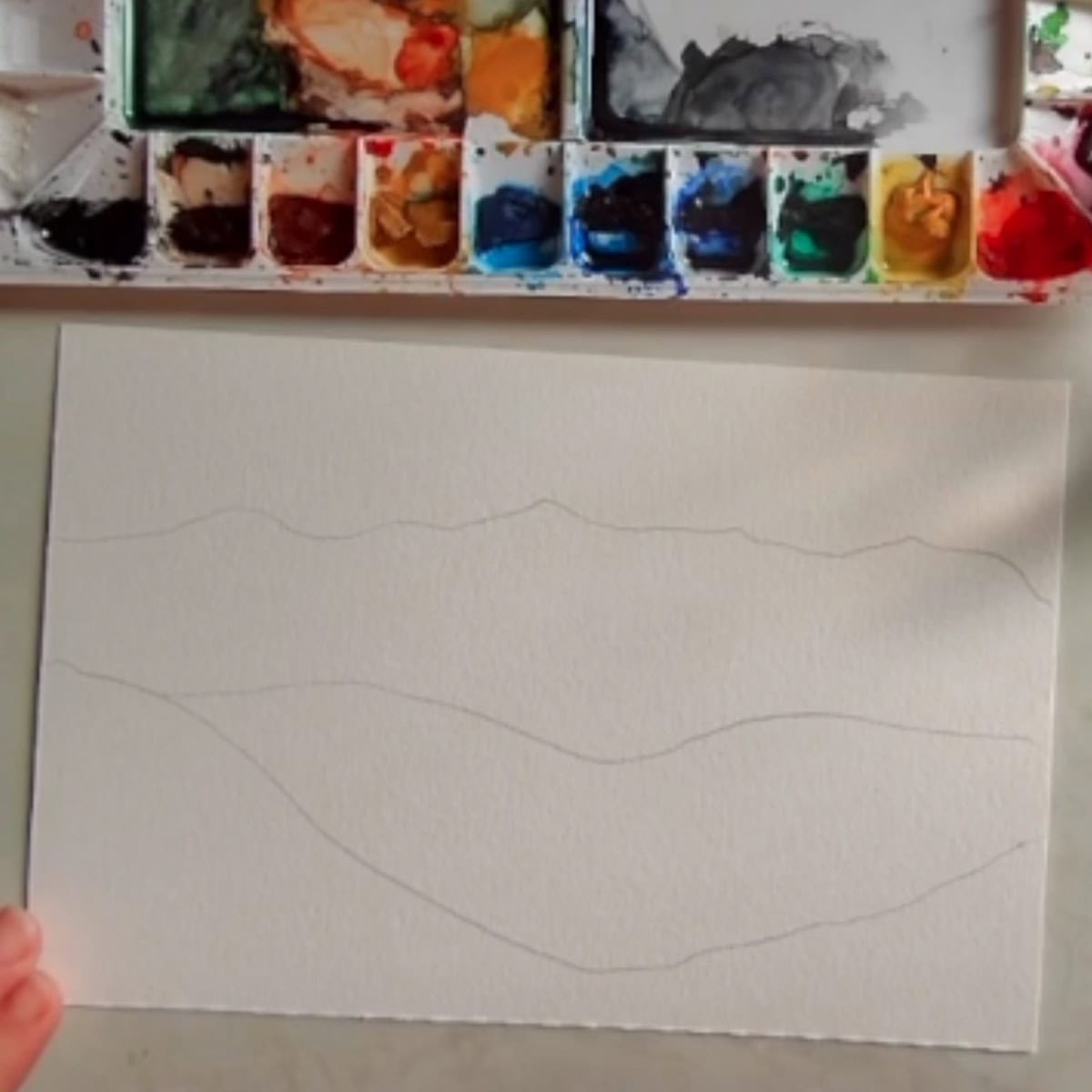 Beginning sketch of a mountain landscape with a watercolor paint palette. 