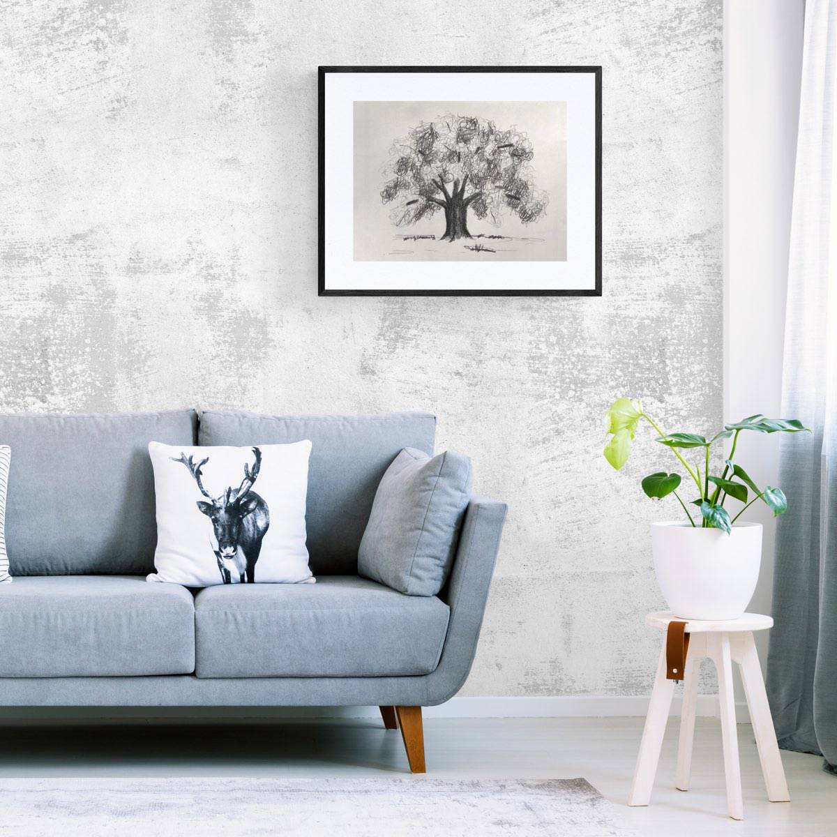 Drawing of an oak tree framed on the wall above a blue couch next to a plant.