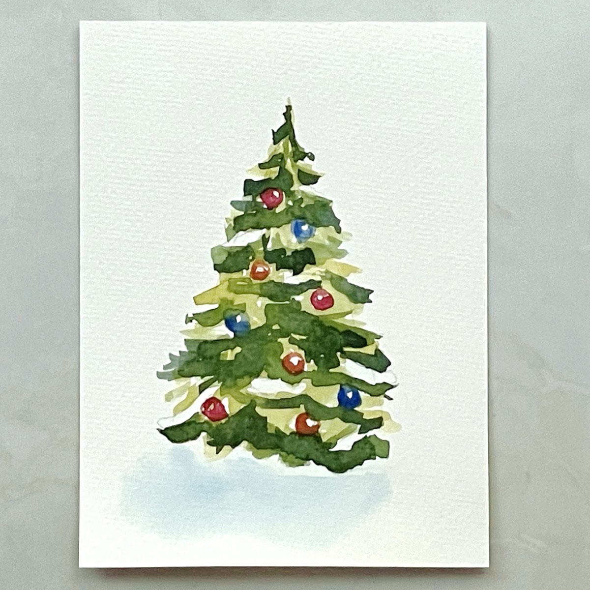 A watercolor painting of a Christmas tree with colorful ornaments and patches of snow.