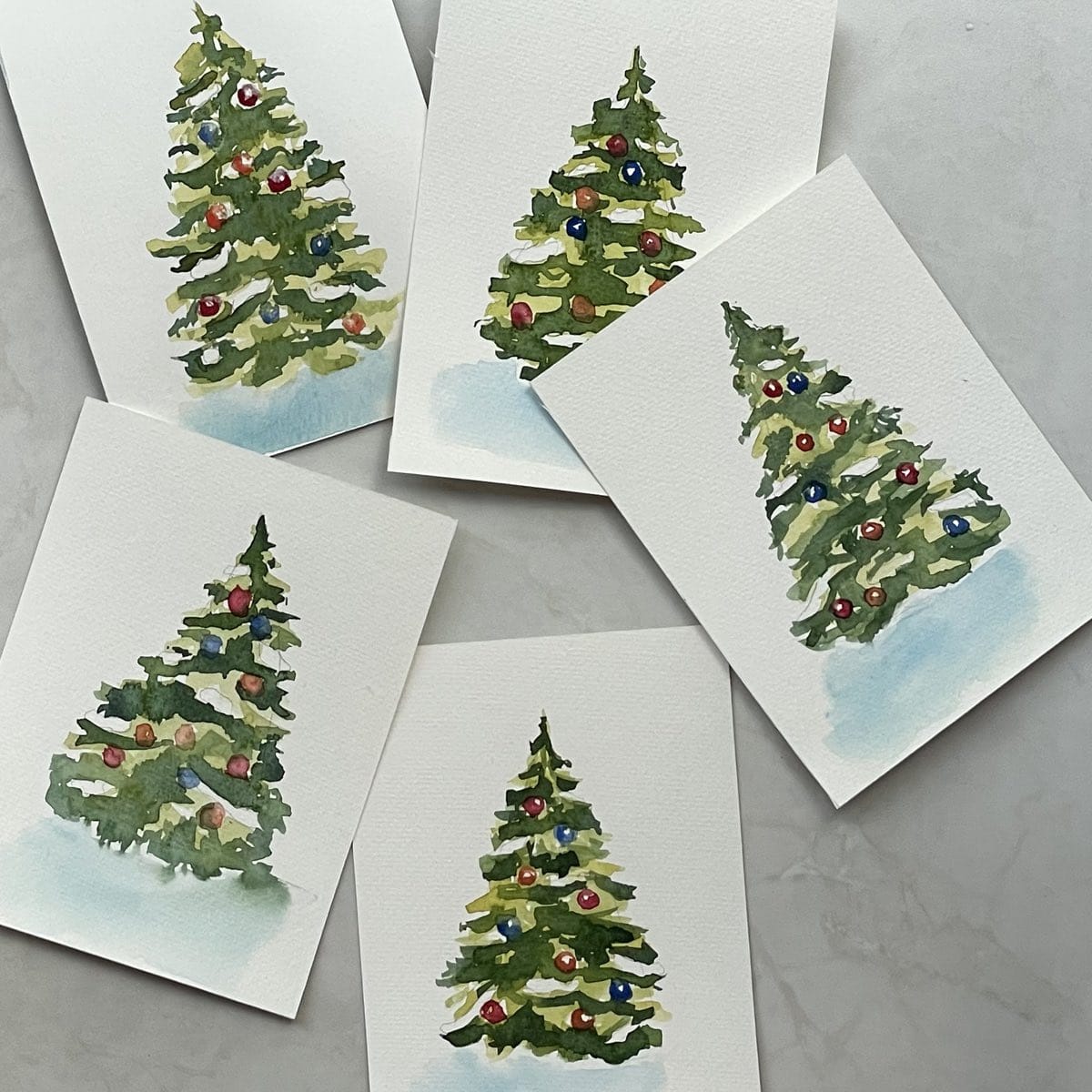 Five watercolor paintings of Christmas trees randomly arranged together on a white background.