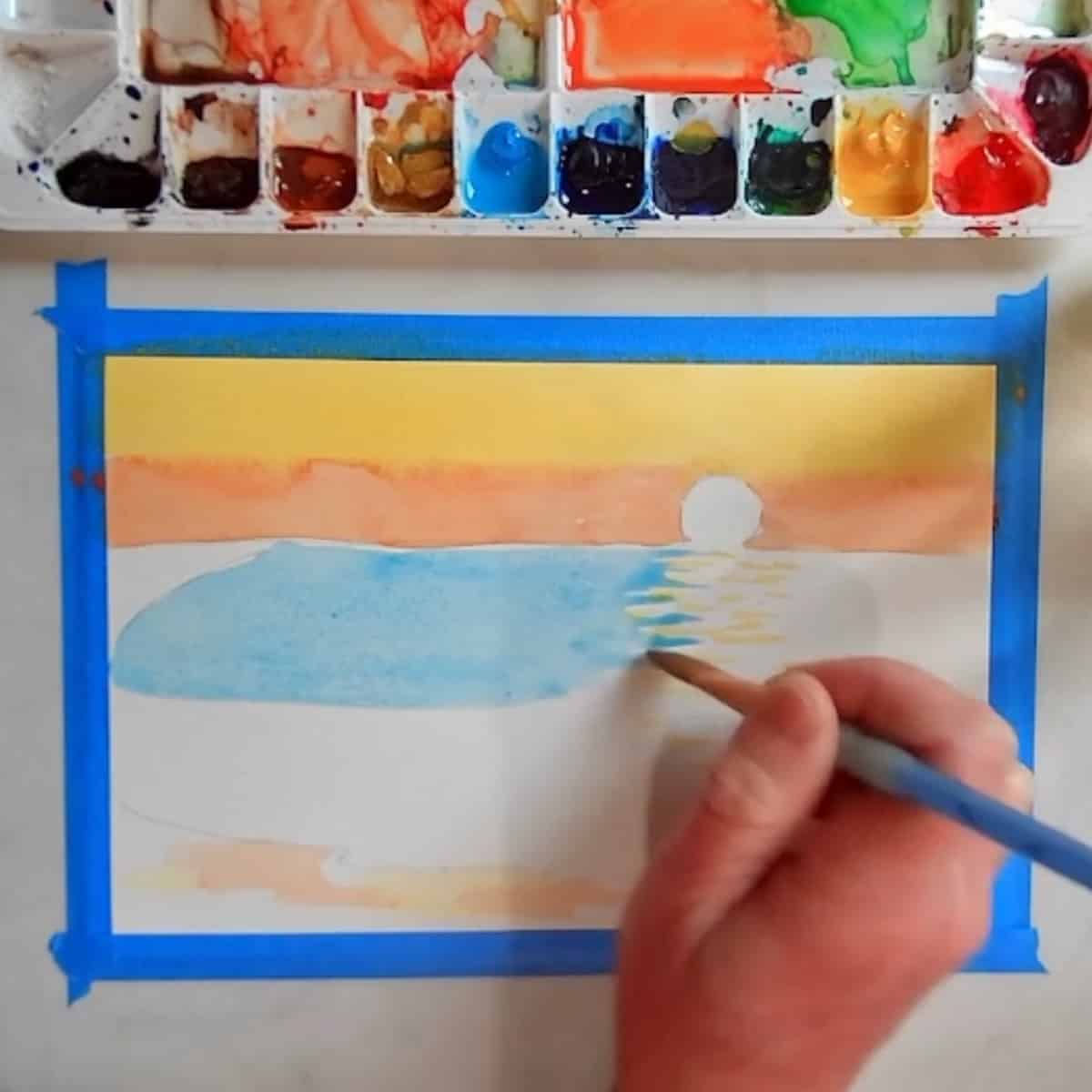 An artist painting in the water in a beach sunset painting.