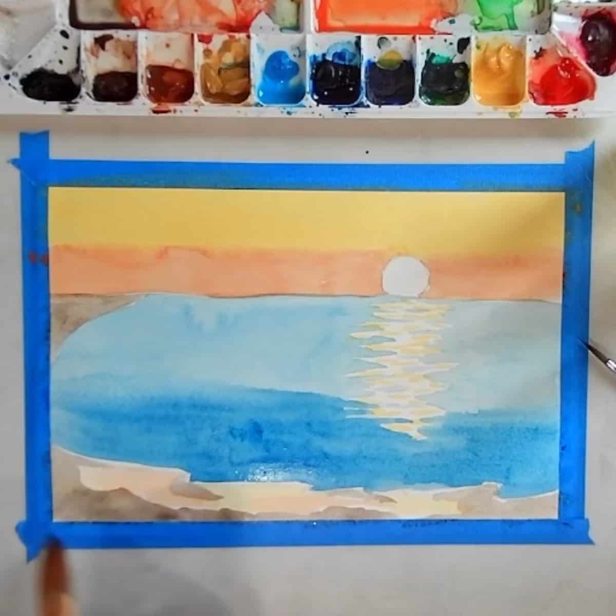 An artist painting in the beach of a watercolor beach sunset painting.