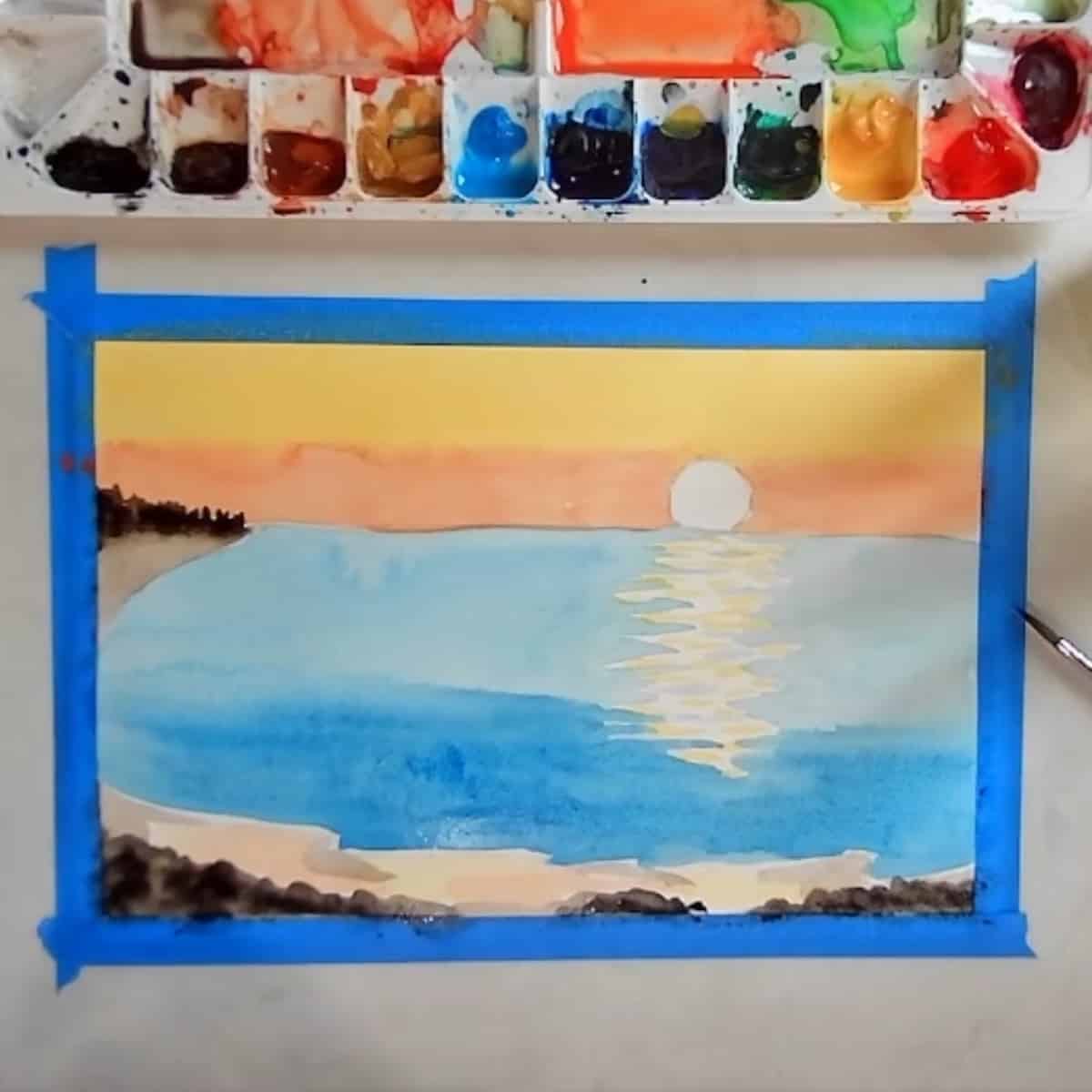 A watercolor painting in progress of a beach sunset.