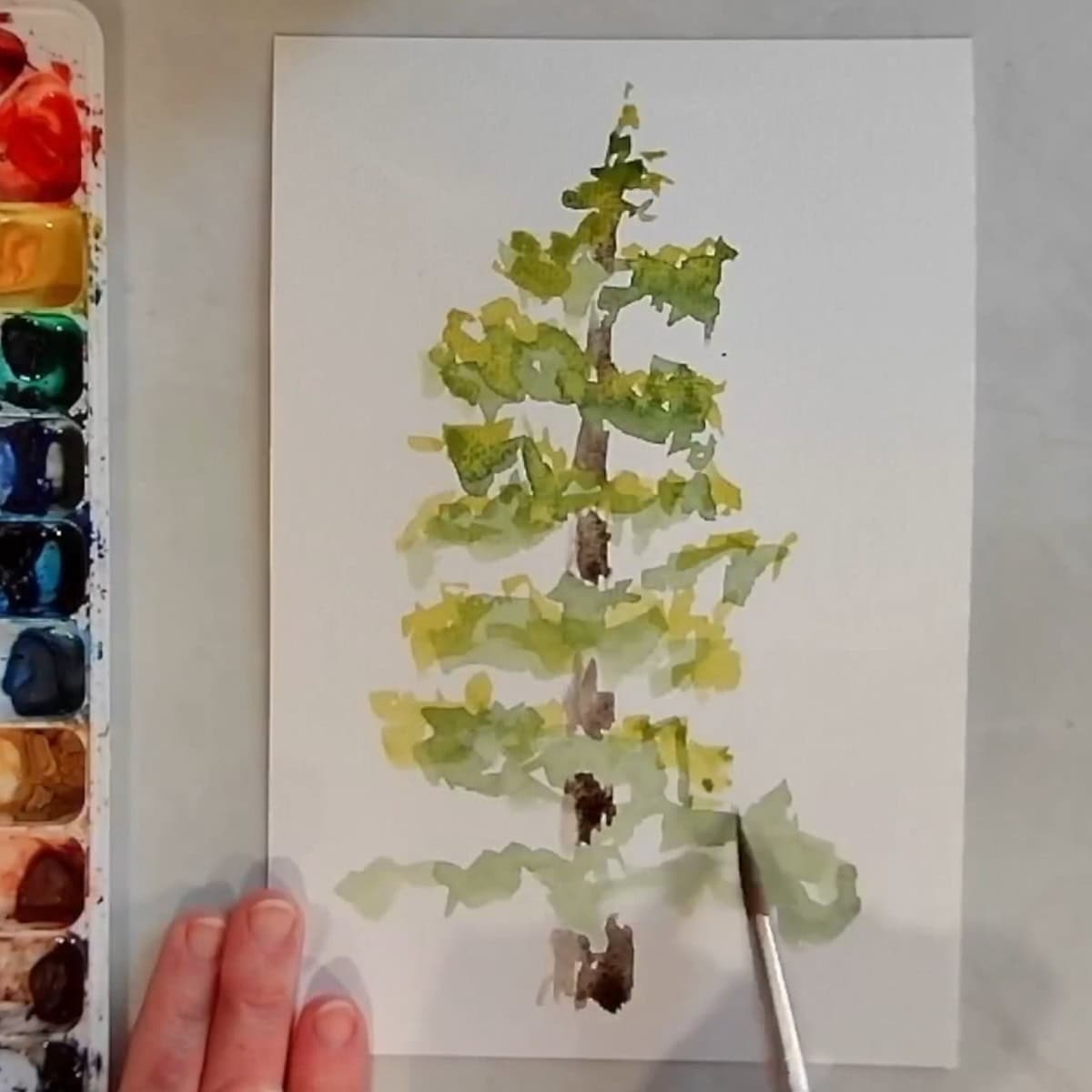 An artist painting light green highlights on an evergreen tree.