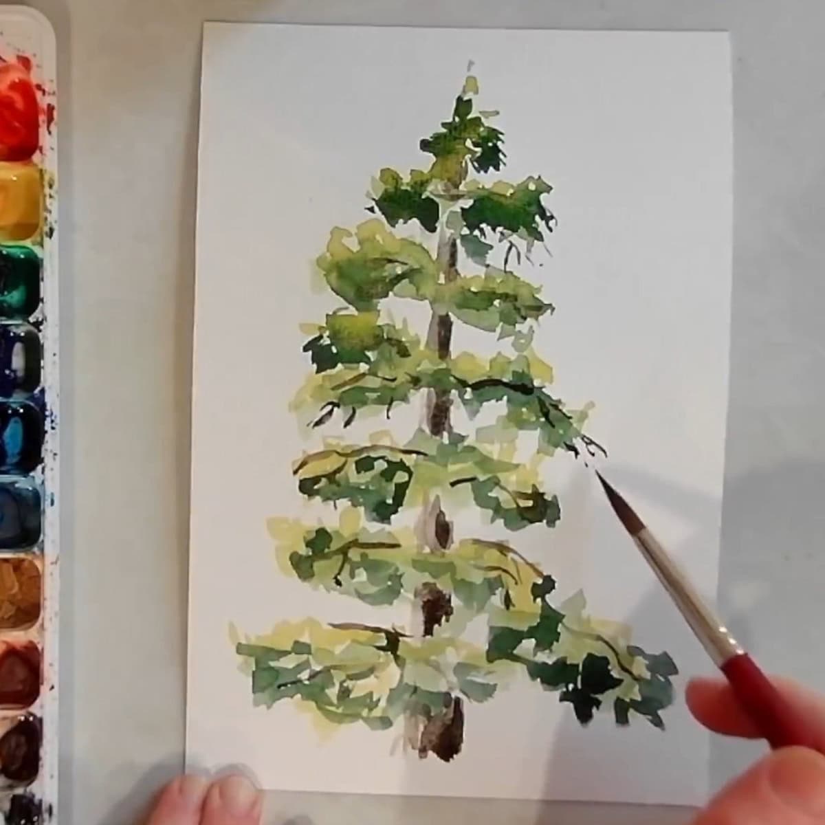 An artist painting branches and twigs on a pine tree.