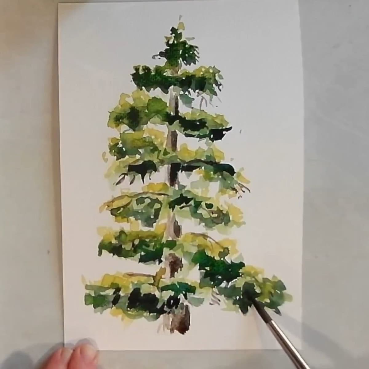 An artist painting dark green shadows on a watercolor pine tree.