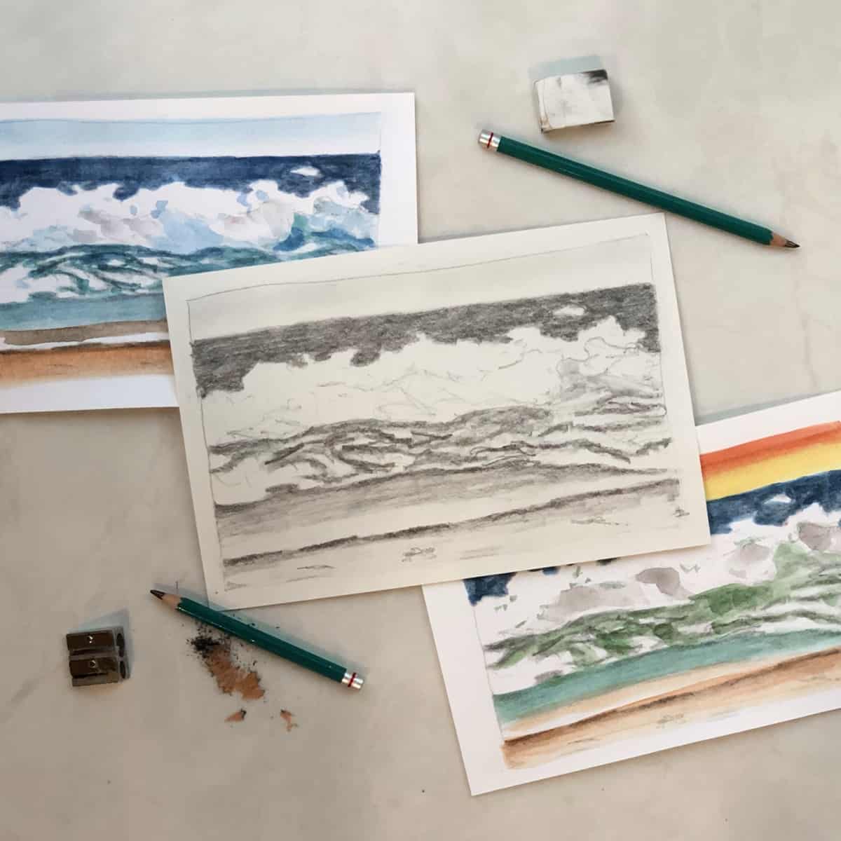 Drawing and paintings of seascapes with pencils, pencil sharpener, and eraser.