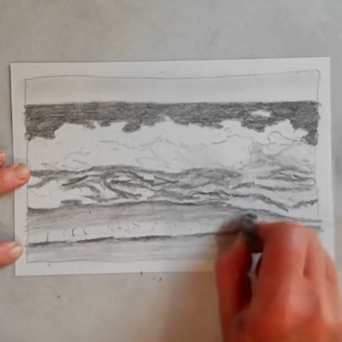 A hand erasing highlights in an ocean scape drawing.