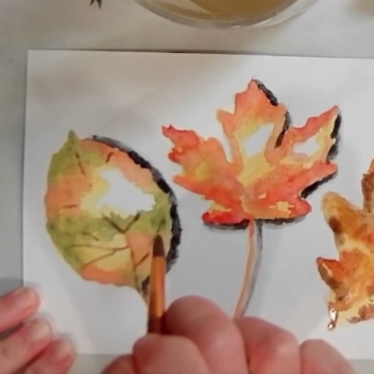 An artist painting the veins in on an autumn leaf.