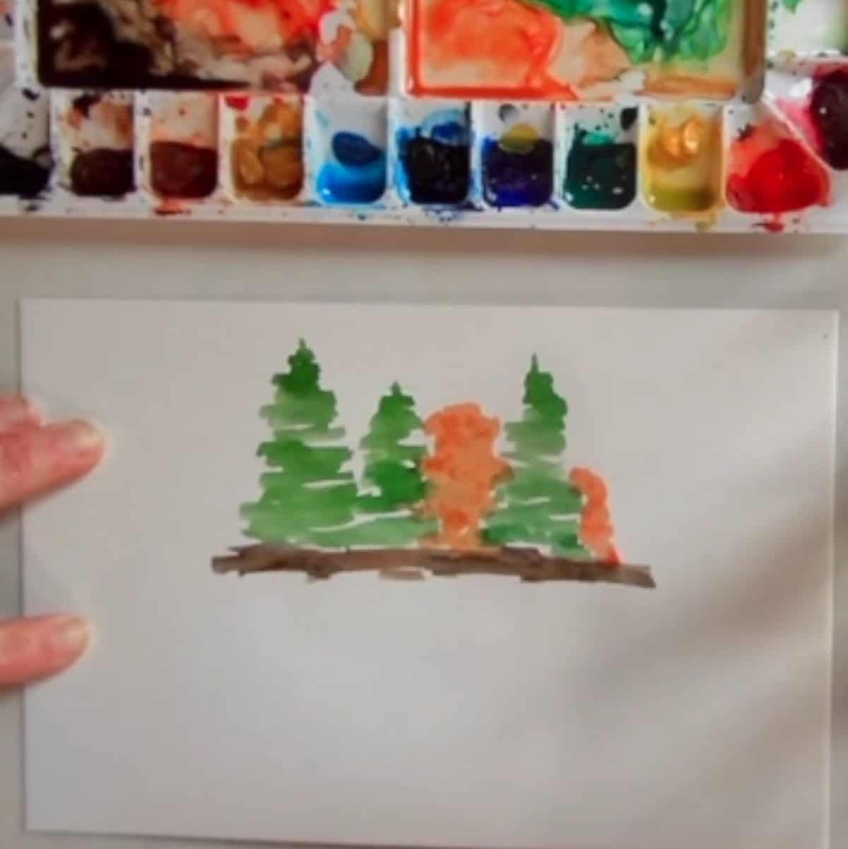 The beginning of a watercolor painting of green and orange trees on land.